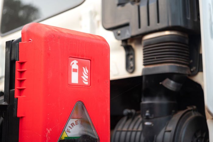 Extincteur de sécurité rouge fixé à un camion, utilisé pour lutter contre les incendies en cas d'urgence.